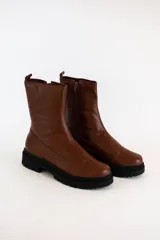 Borcegos de cuero color marrón con suela track negra de goma. Presentan cierre lateral interno y diseño de caña media con puntera reforzada.