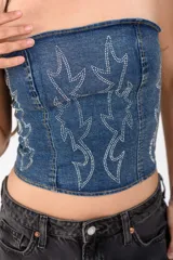 Top strapless de denim negro con efecto acid wash y diseño de stencils de pedrería brillante en el frente.