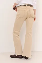 Jean de corte flare color beige, con costuras frontales marcadas y terminación desmechada en el dobladillo.