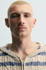 Cárdigan de punto con diseño de trenzas y rayas horizontales en tonos beige y azul. Presenta corte relajado, capucha, cierre frontal con cremallera y puños y ruedo en tejido rib.