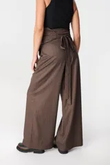 Pantalón de tiro alto con corte holgado y pierna ancha. Presenta bolsillos laterales ocultos en la costura y una faja desmontable ajustable en la cintura.