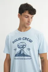 Remera de algodón color celeste, con cuello redondo, manga corta y estampa frontal con diseño de volcán y texto.