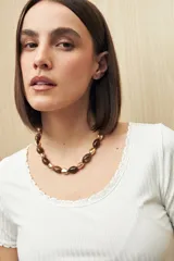 Collar corto con cuentas ovaladas color marrón combinadas con cuentas doradas.