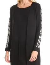 Vestido negro de manga larga con cuello redondo y diseño de cárdigan abierto superpuesto. Presenta un patrón geométrico blanco en las mangas y en el dobladillo.