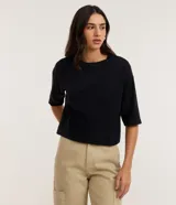 Remera cropped de algodón color negro, con cuello redondo y mangas cortas.