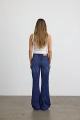 Jean flare de tiro alto, color azul oscuro, con calce ajustado en la parte superior y piernas acampanadas. Cuenta con cierre de botón y cremallera, y bolsillos clásicos.