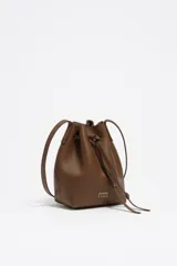 Bolso tipo bucket pequeño de piel vacuna, color marrón, con estructura blanda. Cuenta con asa regulable de piel y cierre de cordón ajustable. Presenta el logo metálico de BIMBA Y LOLA en dorado.