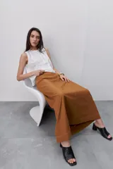 Falda larga color tostado, de línea evasé y silueta amplia, con diseño de paneles y costuras visibles pespunteadas.
