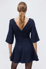 Vestido corto de bouclé color azul marino, con escote redondo, manga francesa, falda con vuelo y detalles de bolsillos decorativos con botones dorados.
