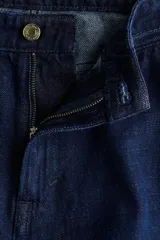 Pantalón de jean de tiro alto con corte recto y pierna ancha. Confeccionado en denim rígido, presenta cierre frontal con botón, bolsillos laterales, bolsillo monedero y bolsillos traseros.