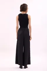 Pantalón largo de tiro alto, color rosa pálido, de corte ancho y fluido. Presenta una hilera de recortes ovalados decorativos a lo largo de la costura lateral.