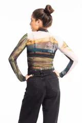 Remera crop top de mangas largas y cuello alto, confeccionada en tejido de red transparente con estampado de paisaje montañoso.