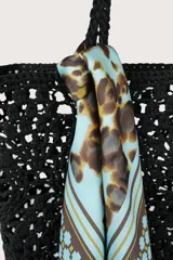 Pañuelo cuadrado con estampado central de manchas tipo animal print en tonos marrones y negros sobre fondo celeste, enmarcado por un borde geométrico con detalles en celeste, marrón y dorado.