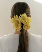Pinza para el pelo con diseño de flores blancas grandes estilo clavel, con mecanismo de agarre tipo clip en tono beige.