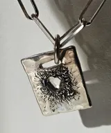 Collar de plata 950 con cadena de eslabones tipo clip y dije rectangular con diseño astrológico grabado y detalles de piedras azules.
