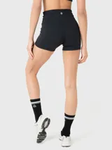 Conjunto deportivo de dos piezas compuesto por un top deportivo con escote en V y espalda estilo nadador, y un short de tiro alto ajustado. Ambas prendas son de color negro y cuentan con un pequeño logo bordado.