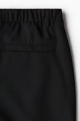 Pantalón negro de tela con corte slim fit, cierre y botón, bolsillos laterales y bolsillo insertado atrás.