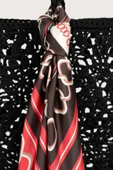 Pañuelo cuadrado con diseño geométrico de cadenas entrelazadas en colores rojo, negro y crema, con borde oscuro y firma central.