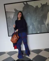 Pantalón de lana a cuadros color beige y blanco, entallado hasta la rodilla y con caída amplia tipo oxford, tajos laterales, elástico en la cintura y cierre oculto.