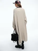 Kimono largo de tejido de punto en color beige, con diseño de sisa caída y mangas abullonadas que aportan volumen. Presenta una silueta relajada y abierta al frente.