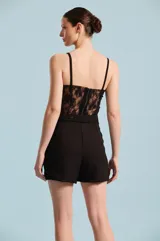 Short negro de tiro alto con cinto incorporado del mismo género con hebilla redonda forrada, bolsillos laterales y dobladillo en las piernas.
