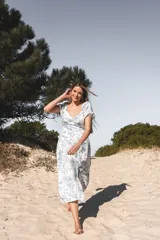 Vestido midi blanco con estampado floral celeste, escote en V, mangas cortas abullonadas y tajo lateral.