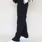 Pantalón negro de corte sastrero con bolsillos cargo laterales, tiro alto y corte recto.