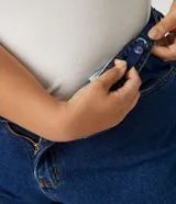 Pantalón mom jeans azul oscuro, tiro alto, con bolsillos delanteros y traseros, trabillas en la cintura, cierre frontal con botón y cremallera, y dobladillo doblado.