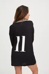 Camiseta negra oversize de manga larga con cuello en V blanco y logo en el pecho.