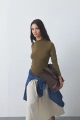 Polera de tejido de punto color celeste, con cuello alto y textura de pequeños puntos en relieve formando una cuadrícula en el frente y las mangas. De corte ajustado y manga larga.