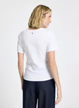 Remera blanca de punto con cuello redondo, mangas cortas, frunce lateral y bajo asimétrico.