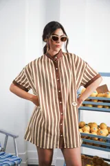 Vestido corto color crema con rayas verticales marrones, cuello mao, botones a tono y parche con logo en el frente.