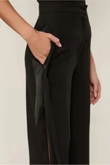 Pantalón negro de crepe sin elasticidad, de calce suelto al cuerpo, con cintura alta, largo completo y aberturas laterales. Cierra mediante botón.