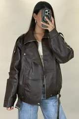 Chaqueta de ecocuero negro con diseño oversize, cuello solapa, cierre frontal y cinturón ajustable en el ruedo.