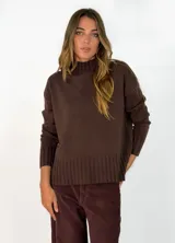 Sweater de punto color marrón chocolate, con cuello alto y puños y ruedo acanalados. Presenta un diseño holgado y mangas largas.