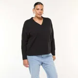 Sweater de punto negro con cuello en V y puños acanalados, de corte holgado y manga larga.