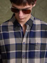 Camisa de manga larga en color azul noche con un patrón de cuadros finos en tonos rojos y verdes. Presenta cuello clásico, cierre frontal con botones y un bolsillo en el pecho con solapa.