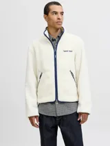 Campera de tejido tipo teddy color crema, con cuello alto, cierre frontal completo y ribetes en color azul marino. Presenta bolsillos laterales con cierre y bordado en el pecho.