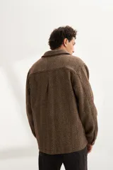 Camisa estilo leñadora marrón con diseño de espiga, cuello clásico, abrochadura frontal a la vista, bolsillos plaqué con tapa en el pecho, mangas largas con puño y botón.