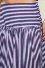 Falda larga de tiro alto con diseño escalonado de paños fruncidos, caída fluida y cierre lateral con cremallera. Presenta estampado de rayas.