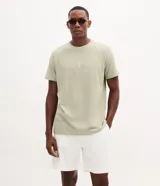 Remera regular de algodón color verde militar, con cuello redondo, manga corta y pequeño estampado frontal de ancora con lettering.