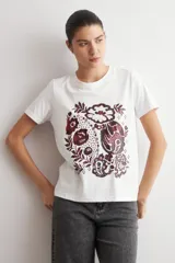 Remera blanca de manga corta con estampado frontal de diseño damasco floral en tonos bordó y marrón.