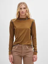 Polera de cuello alto confeccionada en tela rib color blanco, con mangas largas y hombreras. Presenta pespuntes en contraste en las terminaciones del cuello, hombros y puños.