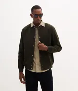 Campera bomber masculina de terciopelo cotelé color beige, con cuello redondo, mangas largas, cierre frontal de botones forrados, bolsillos laterales y terminaciones de elástico en puños y cintura.