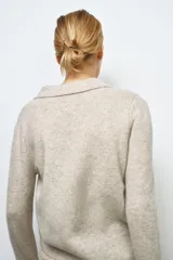 Jersey de lana 100% color beige, con cuello polo, manga larga y botones delanteros.