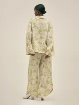 Conjunto de camisa y pantalón de lino color verde con estampado de flores blancas. La camisa es de manga larga y corte holgado.