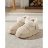 Pantuflas botitas color tostado con diseño acolchado y plataforma, forradas con corderito sintético blanco en el interior y el cuello. Cuentan con una pequeña etiqueta decorativa en el lateral.