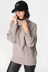 Sweater de punto con textura acanalada, cuello alto tipo polerón, mangas largas con diseño abuchonado y puños anchos.