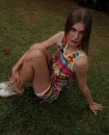 Top de crochet multicolor con diseño de rayas horizontales, cuello redondo y mangas sisa, adornado con flecos colgantes en la parte frontal.