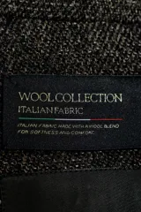 Abrigo largo de mujer, color gris oscuro jaspeado, con cuello solapa de muescas, manga larga y cierre cruzado con botones frontales. Presenta bolsillos con solapa en el delantero y aberturas en el bajo.